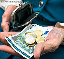 Eine ältere Frau hält in ihrer rechten Hand eine kleine Geldbörse und in ihrer linken Hand ein 5-Euro-Schein und ein paar Münzen.